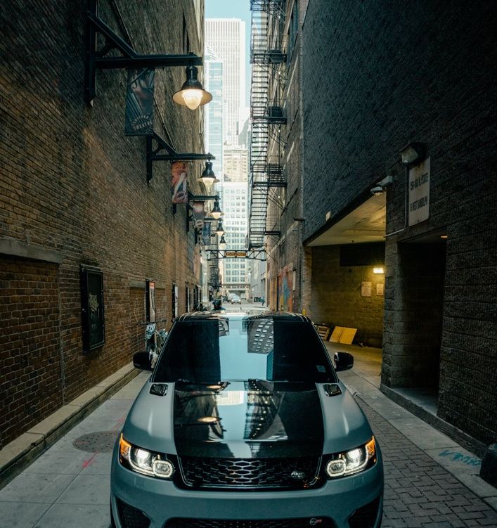 SUV parked in a downtown alley between brick buildings