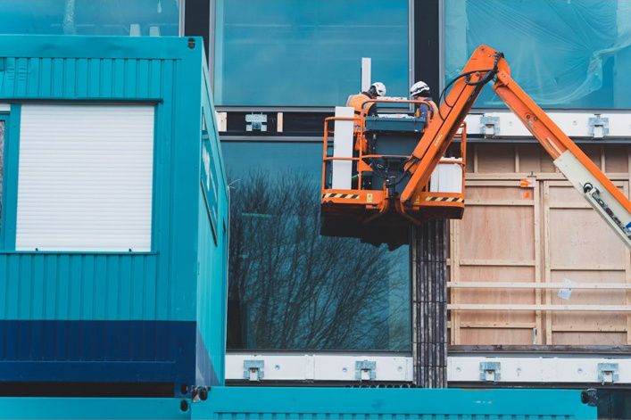 Workers on an aerial lift at a commercial building site