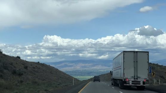 Semi-truck with a trailer on a highway through the hills